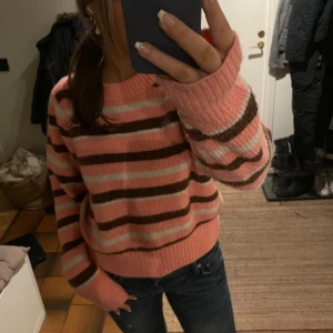Rosa och brun randig stickad tröja - Säljer en mysig stickad tröja i rosa och brunt med randigt mönster. Tröjan har långa ärmar och en rund halsringning. Perfekt för kyligare dagar! Tröjan är från Monki och använd typ 2 gånger🥰 Tröjan finns inte kvar längre!