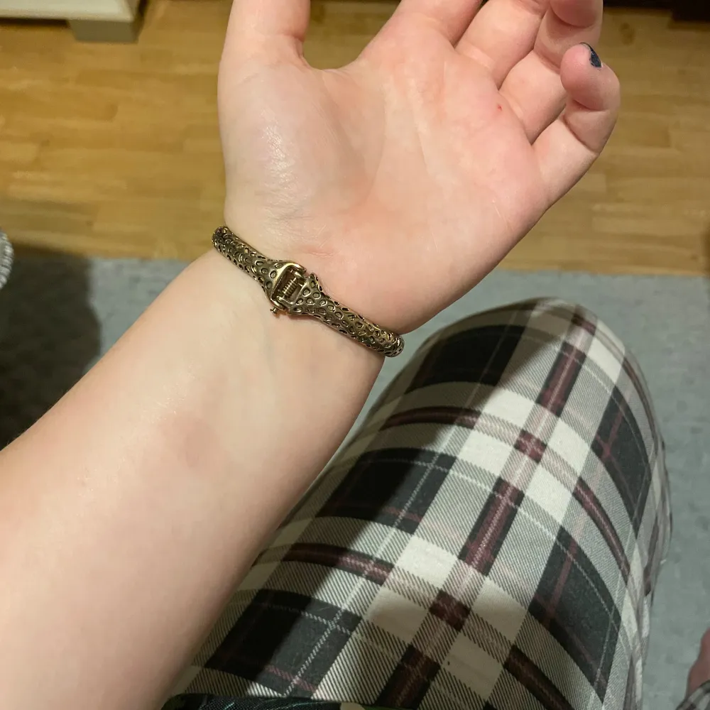 Guldigt armband som ser ut som en cheetah/leopard med gröna ögon. Inte äkta guld.. Accessoarer.