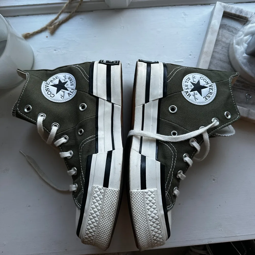 Säljer ett par klassiska gröna Converse All Star sneakers i hög modell. De har vita snören och en vit sula med svarta ränder. Skorna är i bra skick och perfekta för både vardag och fest. Passar till det mesta och ger en cool touch till din outfit! Använda 1 gång så i väldigt bra skick!. Kengät.