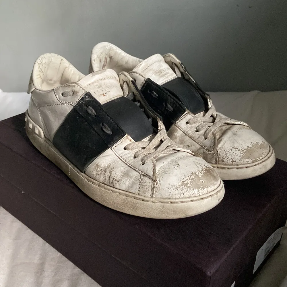 Säljer ett par välanvända Valentino sneakers i skinn. Skorna är vita med svarta detaljer och har en klassisk snörning. Perfekta för en avslappnad stil men behöver lite kärlek för att återfå sin glans.. Skor.