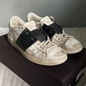 Valentino sneakers i skinn - Säljer ett par välanvända Valentino sneakers i skinn. Skorna är vita med svarta detaljer och har en klassisk snörning. Perfekta för en avslappnad stil men behöver lite kärlek för att återfå sin glans.