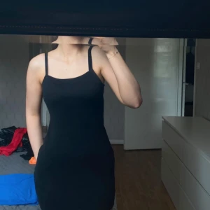 Svart klänning - Säljer en stilren svart klänning med smala axelband. Klänningen har en tight passform som framhäver figuren.