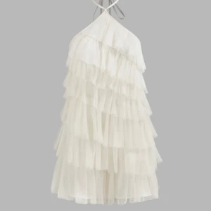 Vit volangklänning - Säljer en superfin vit klänning med volanger som ger en härlig och luftig känsla. Den är axelbandslös och har en öppen rygg med knytband i nacken. Perfekt för sommarens fester eller en speciell kväll. Materialet är lätt och glittrigt, vilket ger en extra touch av glamour. Använd endast en gång. Nypris är 408kr.