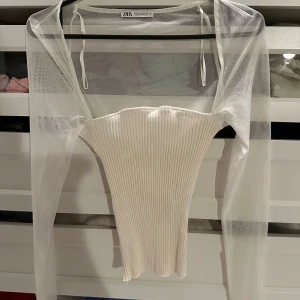 Vit ribbad topp från Zara - Säljer en superfin vit ribbad topp från Zara. Den är axelbandslös och har en tight passform som verkligen framhäver figuren. Perfekt för skolan eller fest! Toppen har en elegant och stilren design 💘