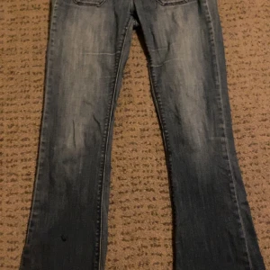 Blå jeans från Roxy - Säljer ett par snygga blå jeans från Roxy. De har en klassisk design med en dragkedja och knapp framtill. Jeansen har en lätt slitning för en cool look och är sjukt snygga.