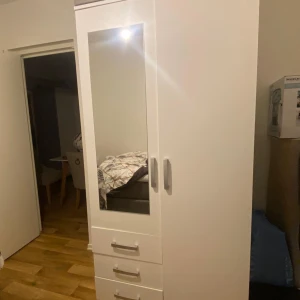 - Säljer en vit garderob i fint skick. Garderoben har två dörrar, varav den ena är en spegeldörr, och tre rymliga lådor nedtill. Perfekt för att förvara kläder, skor och andra tillhörigheter.