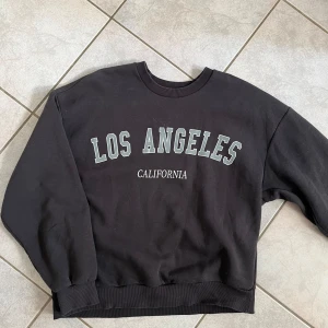 Svart sweatshirt från Gina Tricot - Säljer en svart sweatshirt från Gina Tricot med texten 'Los Angeles California' tryckt på framsidan. Tröjan är i storlek M och har en normal passform. Perfekt för en avslappnad stil eller som ett mysigt lager under kalla dagar. skriv vid frågor💗