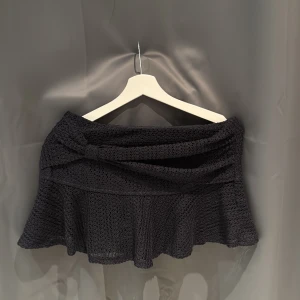 Marinblå kjol med volangdetalj - Snygg marinblå kjol med volangdetalj och omlott-design. Perfekt för att ge en elegant touch till din outfit. Kjolen har en kort längd och är tillverkad i ett lätt material som ger en fin rörelse. Även inbyggda shorts i.