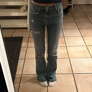 Blå bootcut jeans med slitningar - Säljer ett par blå bootcut jeans med coola slitningar på knäna och fransiga benslut i storlek 34💕💕
