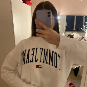 Vit sweatshirt från Tommy Jeans - Vit sweatshirt från Tommy Jeans med deras logga i blått och rött på framsidan. Storleken är i L men är ganska tight, passar bättre någon med 36/38