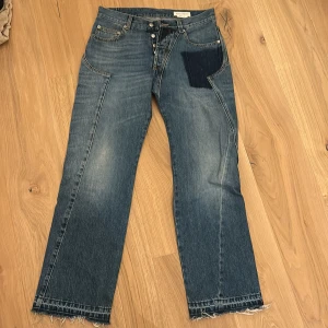Jeans från Alexander McQueen - Snygga jeans från Alexander McQueen med en unik design. De har en patchdetalj på framsidan och fransade kanter vid bensluten. Tillverkade i Italien med högkvalitativt denimtyg.