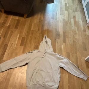 Beige hoodie från H&M Essentials - Säljer en beige hoodie från H&M Essentials. Den har en klassisk design med en stor ficka framtill och en bekväm huva. Perfekt för en avslappnad stil.