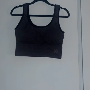 Svart linnetopp från 157 - Säljer en stilren svart sporttopp från lager 157 i storlek medium. Perfekt för träning eller som ett basplagg i garderoben. Toppen har en enkel design med breda axelband och är tillverkad i ett bekvämt material. Använd fåtal gånger.