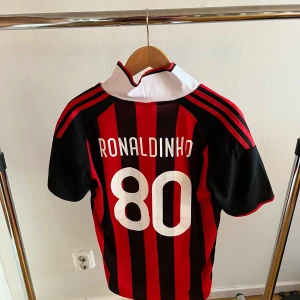 Ronaldinho AC Milan 2009 - Retro AC Milan från Adidas med Ronaldinho och nummer 80 på ryggen. Tröjan har vit krage och korta ärmar. Helt oanvänd!!!!