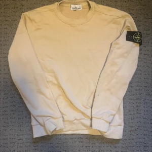 Beige tröja från Stone Island - Säljer en stilren beige tröja från Stone Island. Tröjan har en rund halsringning och långa ärmar med ribbade muddar. Den ikoniska Stone Island-loggan sitter på ärmen. Perfekt för en avslappnad och trendig look. Storlek L men sitter tight på kroppen, så skulle säga att den M. Bara avhämtning i Göteborgsområdet, ingen frakt!