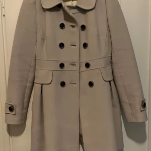 Beige kappa från Karen Millen - Söt, älskad kappa från Karen Millen i strlk 36.   I gott skick förutom nån liten fläck som inte gick bort i kemtvätt.