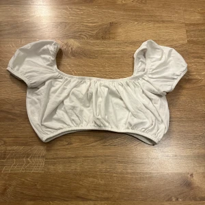 Vit kortärmad topp från NLY Trend - Säljer en söt vit topp från NLY Trend med puffiga korta ärmar och elastisk kant. Perfekt för en somrig look. Toppen är i en mjuk och bekväm bomullsmix.