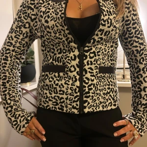 Leopardmönstrad jacka med dragkedja - Snygg leopardmönstrad jacka med dragkedja framtill. Jackan har långa ärmar och svarta detaljer vid fickorna. Perfekt för att ge din outfit en djärv touch.