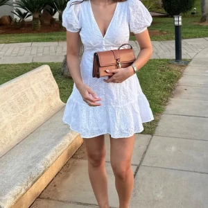 Vit klänning med puffärmar - Säljer en söt vit kortklänning med puffärmar och v-ringning. Klänningen har ett fint broderat mönster och volangdetaljer. Perfekt för studenten! 🌸