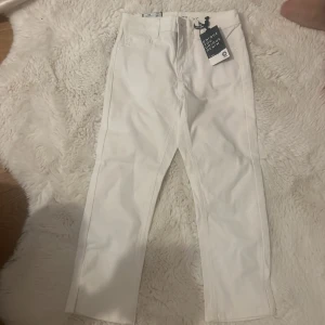 Vita capribyxor från Unique Denim - Snygga vita capribyxor från Unique Denim i midwaist-modell. Perfekta för en stilren look med sin enkla design och bekväma passform. Byxorna är tillverkade i denim och har en klassisk stil som passar till många olika outfits.