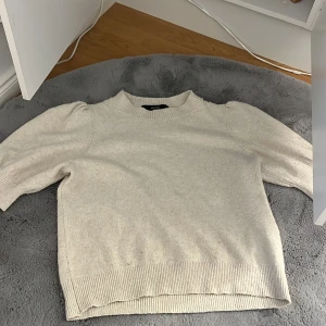 Beige stickad tröja - Säljer en mysig beige stickad tröja med puffiga ärmar. Tröjan har ribbade muddar vid ärmslut och nederkant, vilket ger en fin passform. Den är storlek M men funkar även för alla med strlk S skulle jag säga, från vero Moda, inte använd så mycket eftersom jag själv inte passade inte färgen 