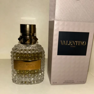 Valentino Uomo Eau de Toilette 50 ml - Säljer en elegant Valentino Uomo Eau de Toilette i en lyxig flaska med diamantmönster och guldfärgad etikett. Flaskan rymmer 50 ml och har en stilren, metallisk kork. Perfekt för den som vill ha en sofistikerad doft.