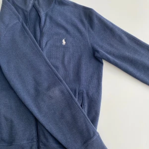 Ralph Lauren Zip tröja mörkblå - Säljer denna då den inte passar, den är storlek S/XS. Riktigt nice färgkombination med mörkblå och vit logga, tröjan är dessutom i överlag bra skick (inga flaws). Den är rätt gammal så etiketten har suddats ut lite. Kom gärna med prisförslag eller frågor!