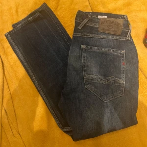 Replay Anbass Mörkblå 33/34 - Snygga blå jeans från Replay i modellen Anbass. De har en klassisk femficksdesign med dragkedja och knapp. Perfekta för en avslappnad stil.