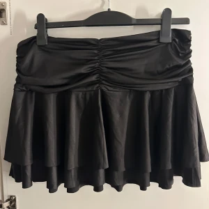 Svart kjol från Monki - Snygg svart kjol från Monki med volangdetaljer och rynkad midja. Säljer då jag inte anser att den kommer till användning längre💕