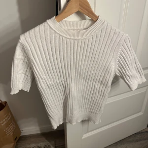 Vit ribbad tröja - Säljer en stilren vit ribbad tröja med korta ärmar. Perfekt för en avslappnad look. Tröjan har en rund halsringning och är gjord i ett mjukt material. Jag har klippt bort lappen men skulle säga att det är en S/M