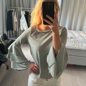 Grön blus med volangärmar - Snygg grön blus med långa volangärmar. Perfekt för en stilren look med en touch av elegans. Blusen har en mjuk och bekväm passform. Märket är Gina Tricot och storlek S