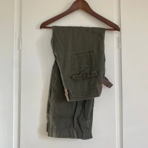 Mörkgröna cargobyxor  - Mörkgröna cargobyxor i bra skick! Midjemått 74 cm och innerbenslängden 76 cm