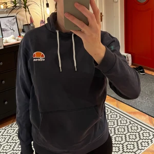 Mörkblå hoodie från Ellesse - Säljer en mörkblå hoodie från Ellesse i storlek S. Finns ett litet hål på vänstra ärmens baksida, ungefär vid armbågen. 