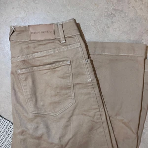 Beige byxor från Carin Wester - Snygga beige byxor från Carin Wester med klassisk design. De har en dragkedja och knappar framtill samt praktiska fickor. Perfekta för en stilren look. Knappt använda!