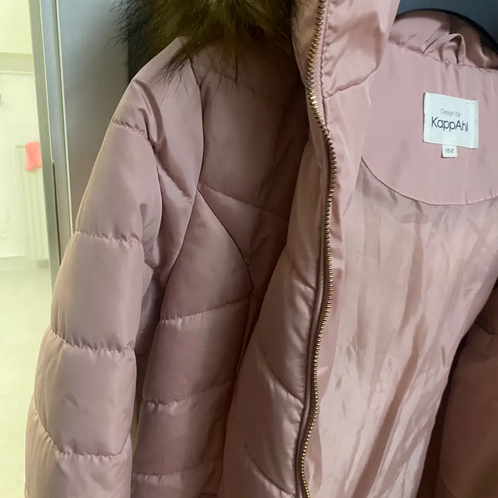 Säljer en snygg rosa quiltad jacka från KappAhl med en mysig pälskantad huva. Jackan har dragkedja framtill och är perfekt för kyligare dagar. Den är både stilren och praktisk med sin varma design.. Takit.