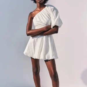Vit oneshoulder klänning - Snygg vit oneshoulder klänning med puffig ärm. Perfekt för en somrig look med sin lätta och luftiga design. Klänningen har en elegant och modern stil som passar perfekt för varma dagar. Passar perfekt antingen till sommaren eller studenten🤩