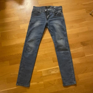 Blå Replay anbass jeans - Snygga blåa replay anbass jeans. Materialet är slitstarkt och bekvämt. Finns en defekt och de är att de har blivit ett hål men det har limmats igen med jeans material och textillim 