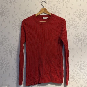 Röd ribbad tröja från Weekday - Säljer en snygg röd ribbad tröja från Weekday. Tröjan har en klassisk rund hals och långa ärmar, perfekt för kyligare dagar. Den är både stilren och bekväm, ett måste i garderoben!