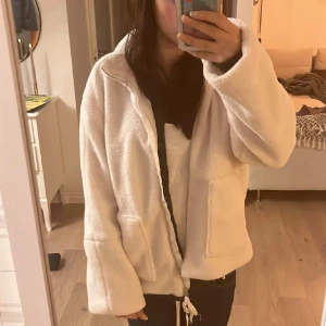 Vit teddyjacka med dragkedja - Mysig vit teddyjacka i storlek S med dragkedja framtill och två stora fickor. Perfekt för väder som nu. Jackan är köpt här på plick av en annan tjej (första bilden är tagen från henne), jackan köptes oanvänd och har nu använt fåtal gånger. Mycket fint skick. Säljer då den är lite liten på mig💕