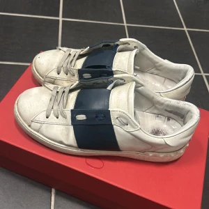 Valentino Garavani Opens - Snygga Valentino Garavani sneakers i vitt med en bred mörkblå rem över snörningen. Dem är 100% äkta vad jag vet och dem är använda låda med kommer