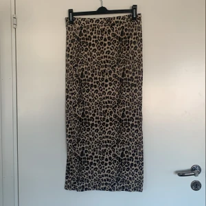 Leopardmönstrad kjol från Black Label Collection - Snygg leopardmönstrad kjol från Black Label Collection i storlek XS. Kjolen har en klassisk leoparddesign i beige och svart, perfekt för att ge en trendig touch till din outfit. Den är i en längre modell och passar bra för olika tillfällen.