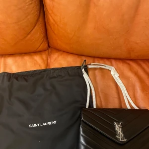 Svart axelväska från Saint Laurent - INTRESSEKOLL!! På min oanvända ysl väska. Den är i nytt skick och har inga tecken på användning. Jag kan inte garantera att den är äkta då jag inte har kvittot men original påsen finns kvar. Skriv vid intresse och ge gärna prisförslag! ❤️