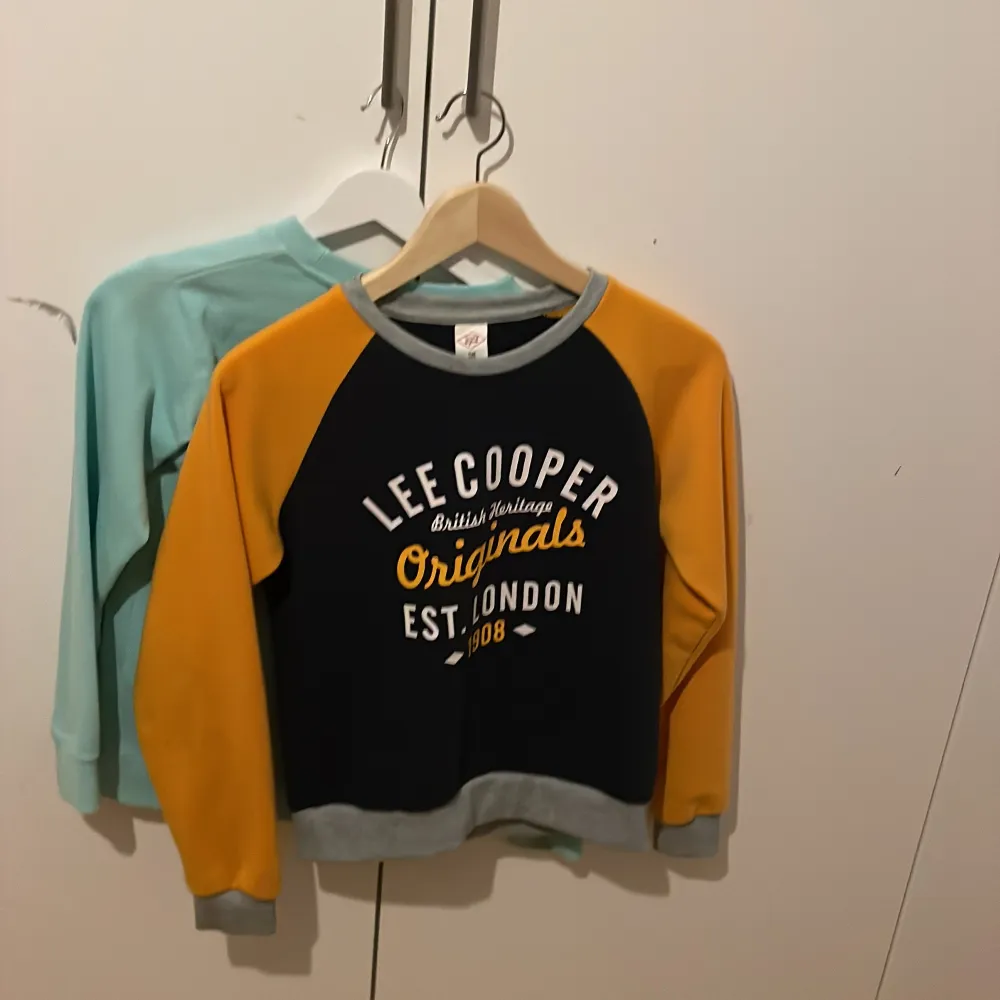Säljer två snygga tröjor. Den första är en Lee Cooper tröja i svart och orange med tryck framtill. Den andra är en mintgrön Pull&Bear tröja med ett tryck av Santa Monica Beach. Båda har långa ärmar och rund halsringning.. Neuletakit & Villapaidat.