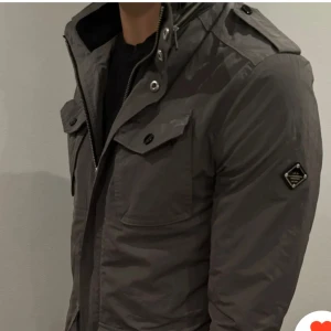 Grå J. Lindeberg jacka - Säljer en stilren grå jacka från J. Lindeberg. Storlek M och jackan är i bra skick. Nypris: 3999kr. Mitt pris 1399kr men kan sänkas vid snabb affär