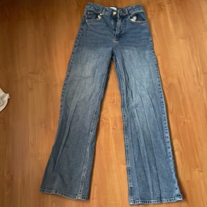 Blå jeansbyxor - Snygga blå jeansbyxor med en klassisk design. De har en högmidjad passform och raka ben som ger en avslappnad look. Perfekta för en casual stil.