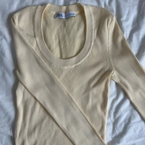 Gul ribbad tröja från Zara - Säljer en stilren gul ribbad tröja från Zara. Tröjan har en rund halsringning och långa ärmar, perfekt för lager på lager under kyligare dagar. Passar både till jeans och kjol för en avslappnad look.
