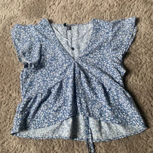 Blå blommig blus från Vero Moda - Säljer en söt blå blommig blus från Vero Moda i storlek XS. Jätte fint till sommaren 