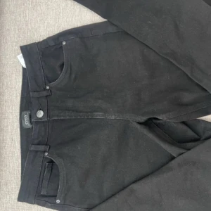 Svarta jeans från ONLY - Snygga svarta jeans från ONLY med klassisk femficksdesign och knappgylf. Perfekta för en stilren look. Märkesdetaljer på baksidan och knappen ger en extra touch.