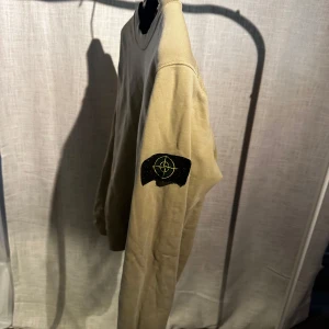 Beige Stone Island tröja - Säljer en beige tröja från Stone Island med deras ikoniska emblem på ärmen. Riktigt go 