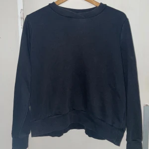 Svart sweatshirt - Säljer en klassisk svart sweatshirt med rund hals och långa ärmar. Perfekt för en avslappnad stil. Tröjan har ribbade muddar vid ärmslut och nederkant.
